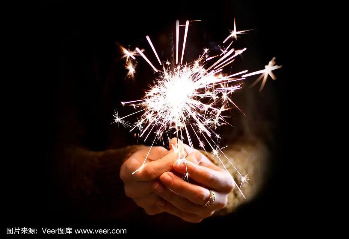 女孩的手拿着一个烟花.在黑暗中.的夜晚.孤立在黑色背景上