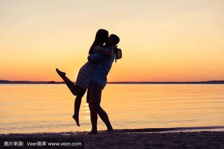 日落时分,海滩上一对幸福的夫妇的剪影,男人把女孩搂在怀里.
