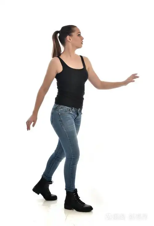 穿黑色单和牛仔裤的黑发女孩的全长肖像.站立姿势, 侧面轮廓.