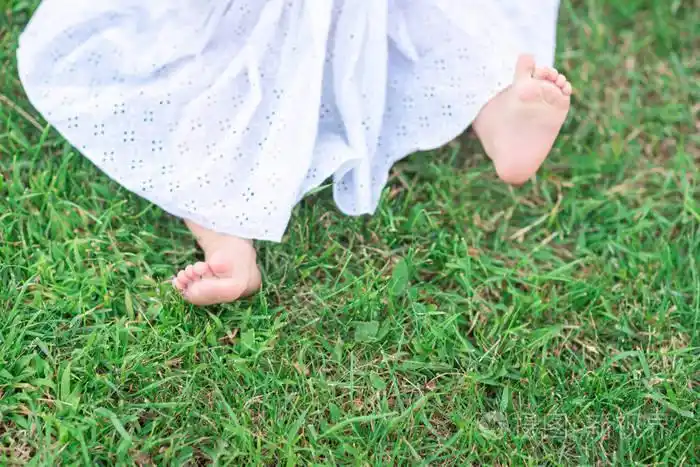 在花园里绿草的孩子赤脚的腿.快乐母性的概念.夏天