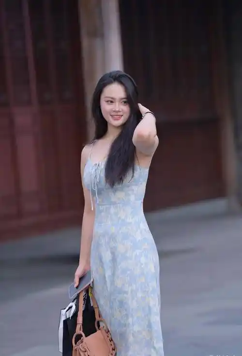 身材时尚的美女,穿了一条淡蓝色的吊带连衣裙,远看清新靓丽,近看时尚
