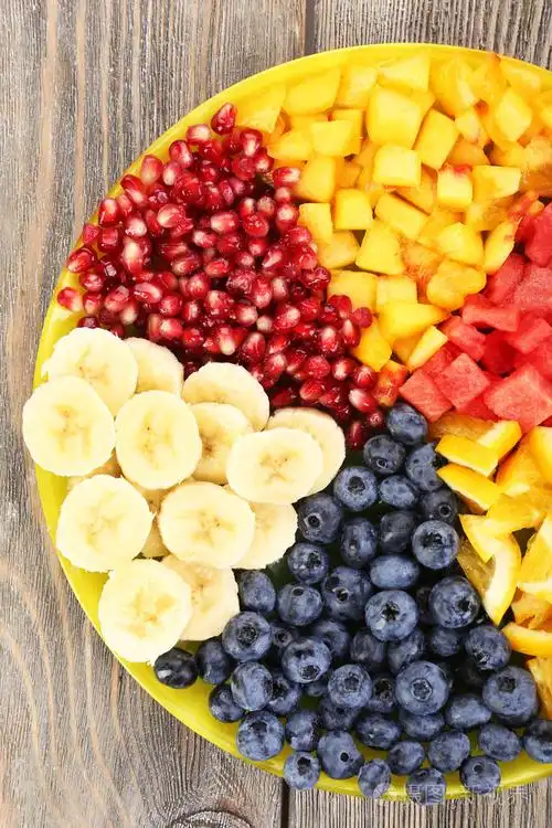 在木制的桌子上的盘子切水果