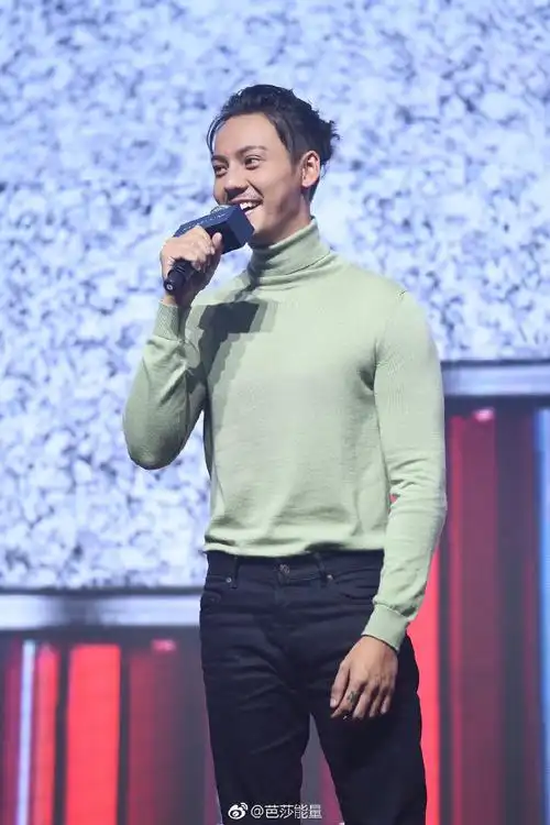 陈伟霆身穿浅色高领针织衫,黑色长裤,梳着丸子头出席某品牌发布会现场