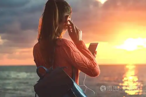 一个年轻快乐的女人在日落时听音乐在海滩上享受美丽的海景旅行和放松