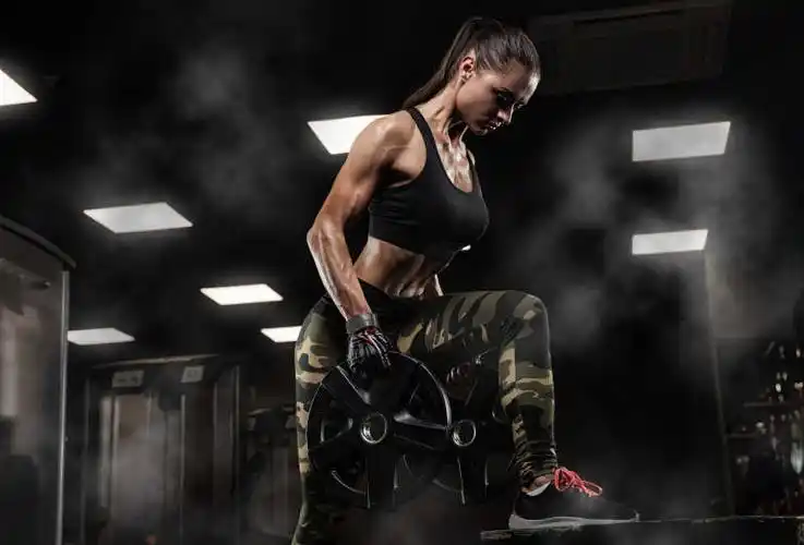 年轻性感的健身女孩在健身房锻炼哑铃