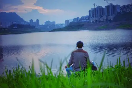 2016年6月12日,重庆万州天仙湖湖畔,一名男子带着耳机在湖边听歌,膝盖