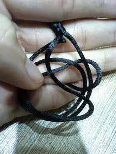 6  另一条绳子绕过左上边的绳子也穿进中间的圆里,这样就穿好了,再