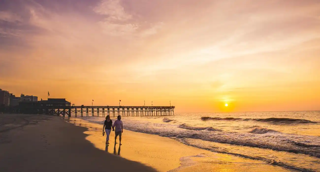 一对情侣在日落日落时分于默托尔海滩上散步