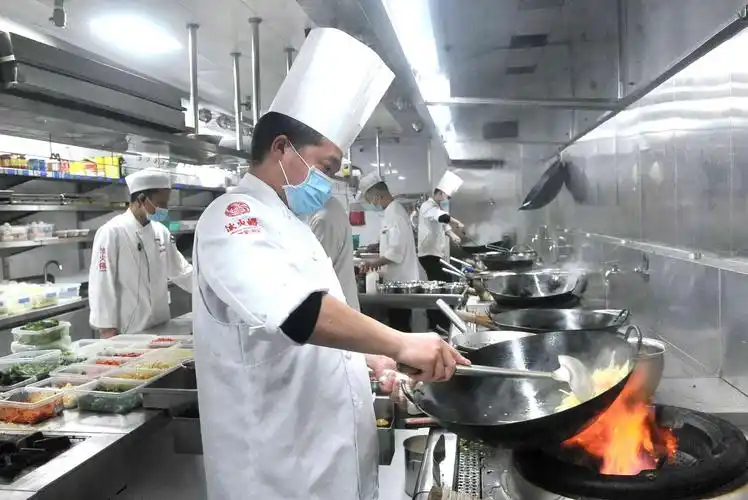 大厨在忙碌着炒菜.至今,冰火楼梦泽园店客流已恢复到疫前的五六成.