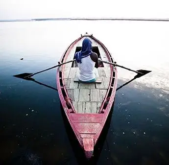 一名男性在湖面上划船的背影