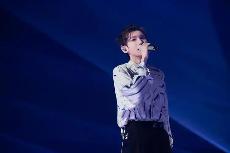 67中,王源身着设计感衬衫,幽蓝的灯光下,他手握黑色话筒,十指修长而