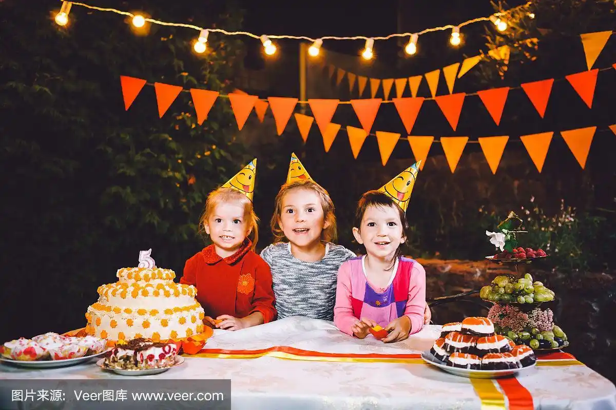 孩子的生日聚会.三个欢快的小女孩坐在桌前用手抹着脸吃蛋糕.