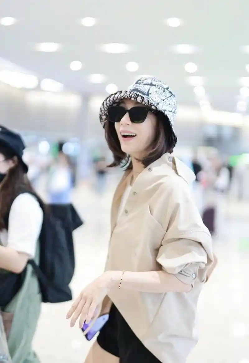 贾静雯机场街拍,卡其色衬衫配白衬衫,黑色短裤 短靴减龄!