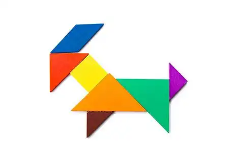 白色背景上山羊形状的彩色木七巧板照片