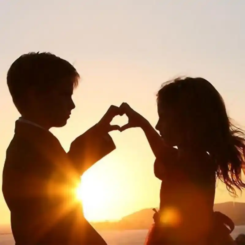 求小男孩和小女孩夕阳下用手拼爱心的高清图
