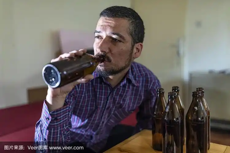 年轻悲伤的醉酒男子喝啤酒和酒精感到浪费,孤独和绝望的痛苦和情绪