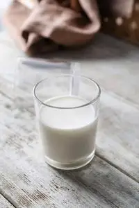 木制桌子上的一杯鲜牛奶照片