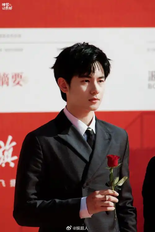 胡先煦穿着黑西服拿着一枝红玫瑰走地毯,还对粉丝比心这哪里是在走