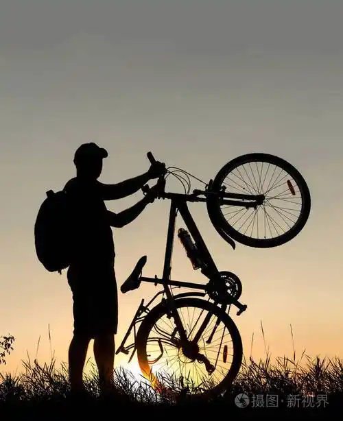 一个骑自行车的男人在日落时背着背包骑着自行车