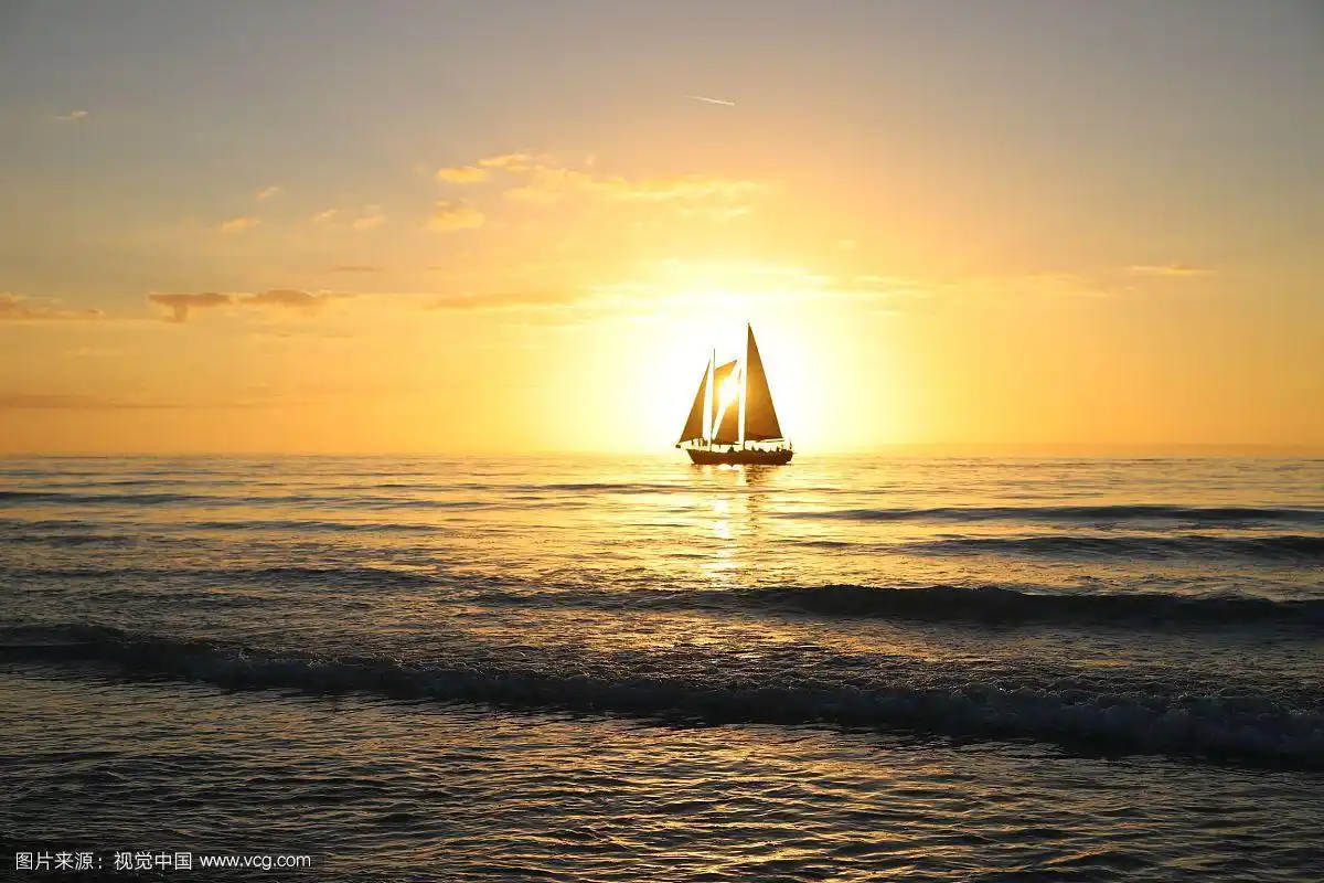 日出时海上帆船的剪影