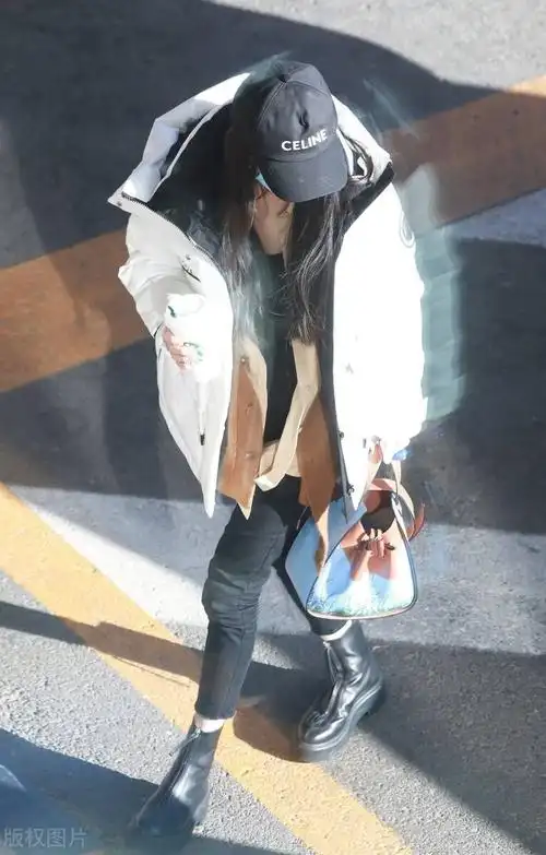 杨幂穿搭一件白色的长款羽绒服,头戴了一个黑色的棒球帽低调现身_机场