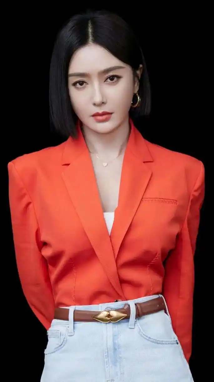 秦岚身着橘红色西服上衣,配一件高腰做旧包臀牛仔短裙,脚穿一双黑白