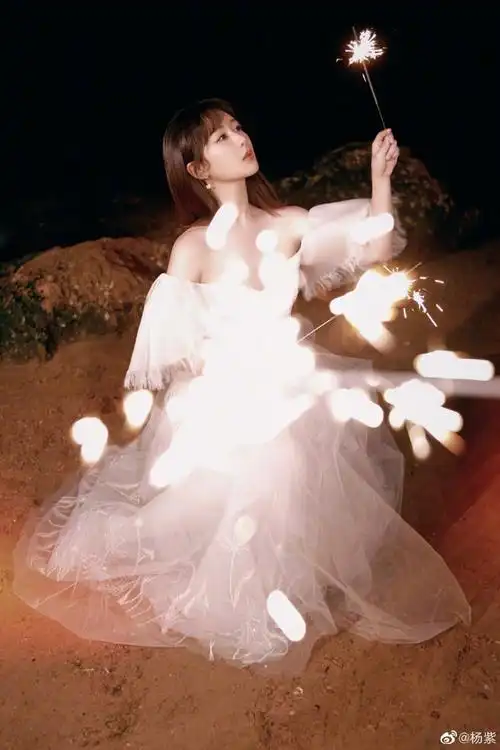 照片中的她身穿白色露肩公主纱裙,手拿仙女棒回眸瞬间仙气飘飘