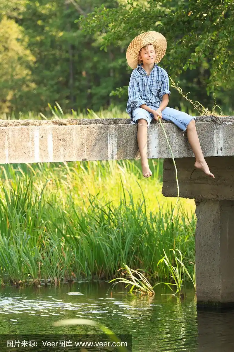 光脚男孩闭着眼睛笑眯眯地垂钓在桥上