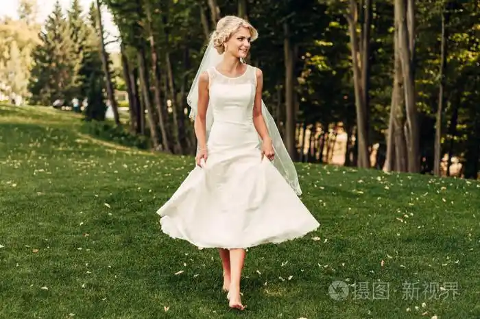 赤脚年轻的 fair-haired 新娘沿着草地走