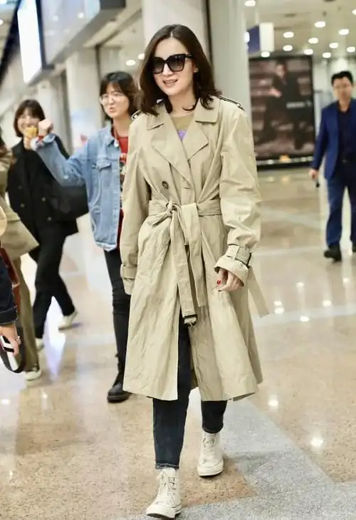女明星手握暖宝现身机场卡其色系带风衣出行展现出女性的独立