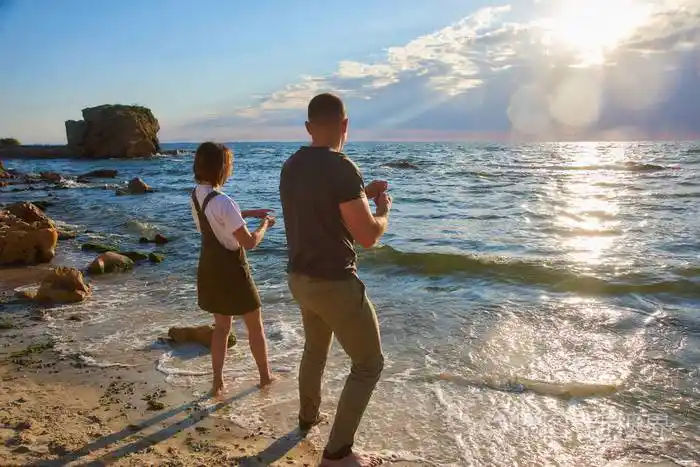 一对幸福的情侣在海边的沙滩上迎接日出玩耍镜框里阳光耀眼