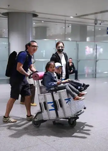 梅婷一家四口走机场,穿白色t恤配蓝色百褶裙,减龄又时髦