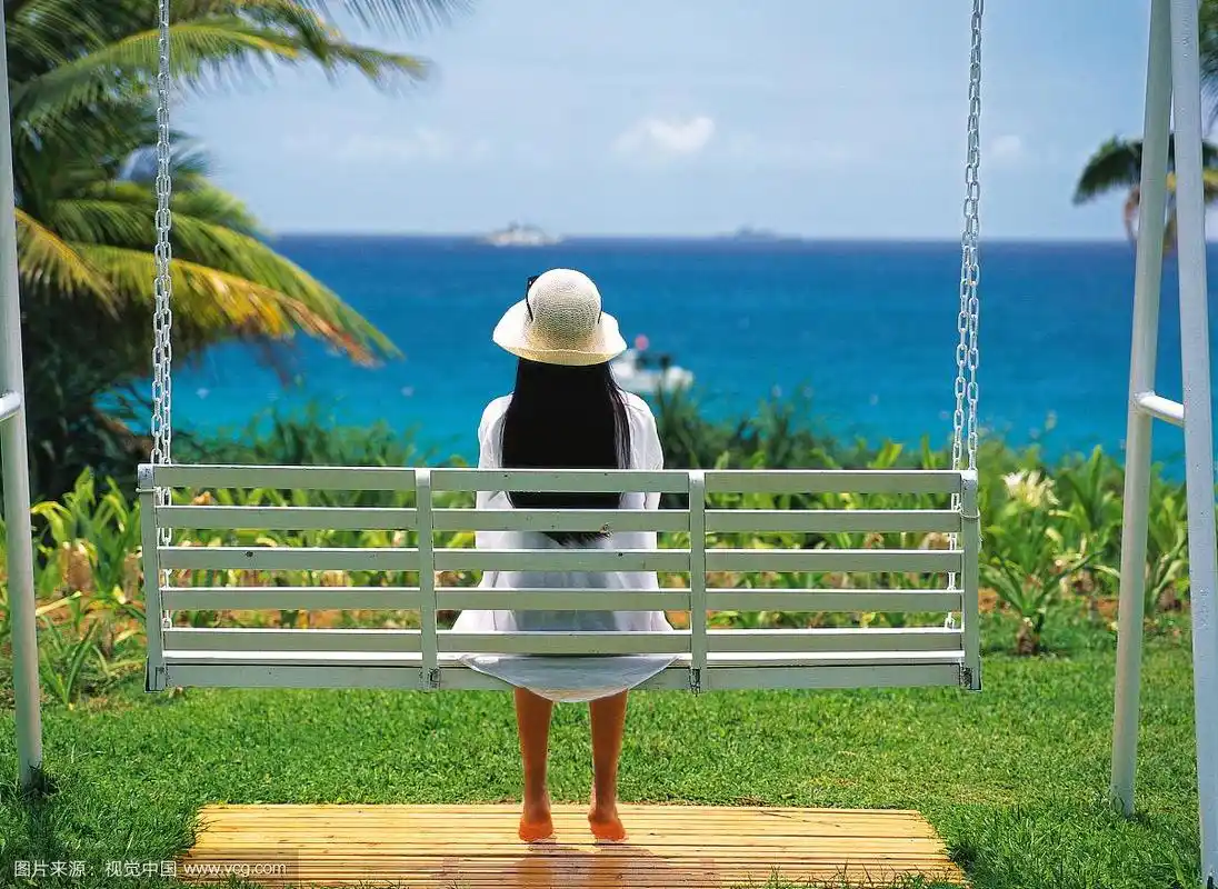 东方女人坐在海边长椅上的背影