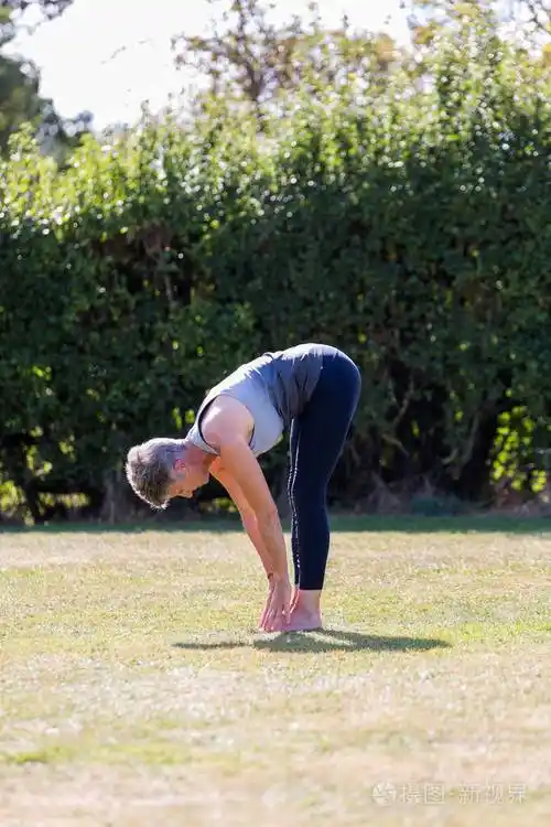一个中年妇女赤脚在草地公园里练习瑜伽照片-正版商用图片2oyotn-摄图