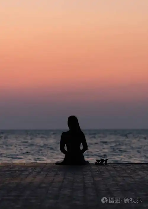 一个女孩在日落背景(日出)上的剪影在海平线上. 夏天在海滩上散步.