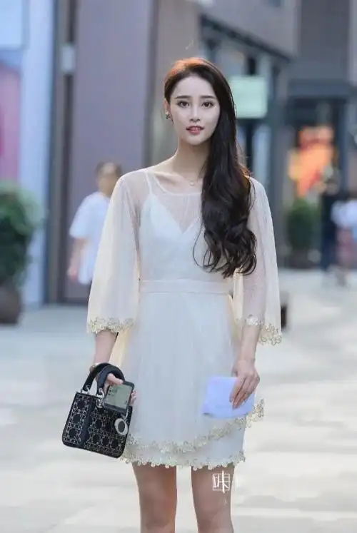 美女皮肤白皙,穿白纱裙显得格外有气质,头发侧分到一边,多了几分女