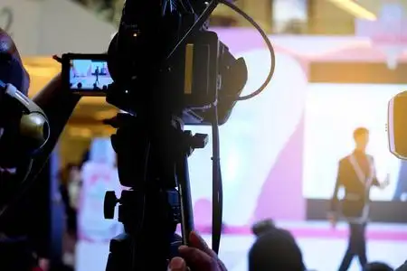 在事件中的摄影师视频录制活动专业视频制作摄像机录制现场活动上台.