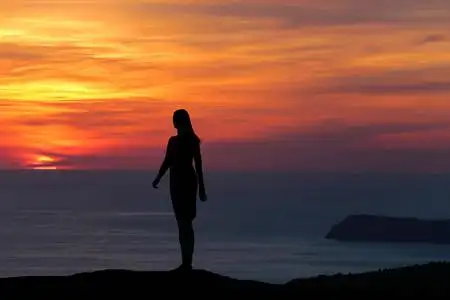 手牵着手, 与大海和蓝天在背景美丽的女人坐在木栅栏上,望着大海纪ゥ