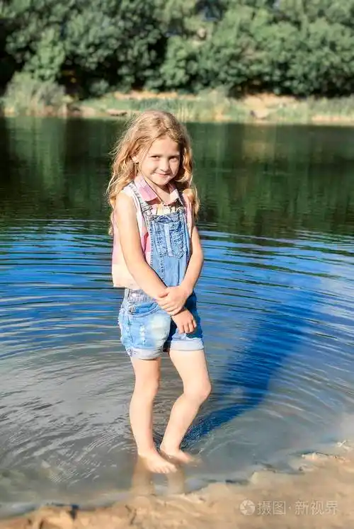 可爱女孩站在赤脚在河里阳光明媚的夏日
