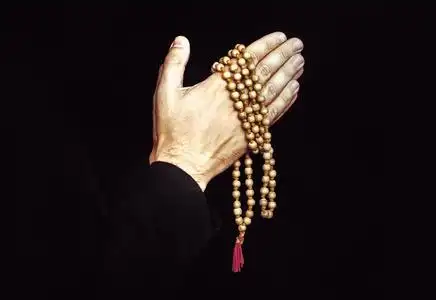 双手合十在祈祷上孤立的黑色背景.在祷告中牧师.在男人手中的念珠照片