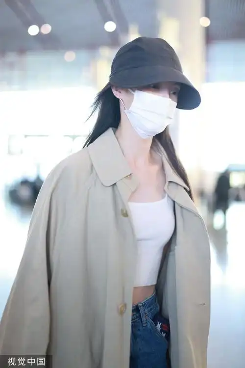 组图:金晨一身风衣造型现身机场 穿露脐装秀优越马甲线