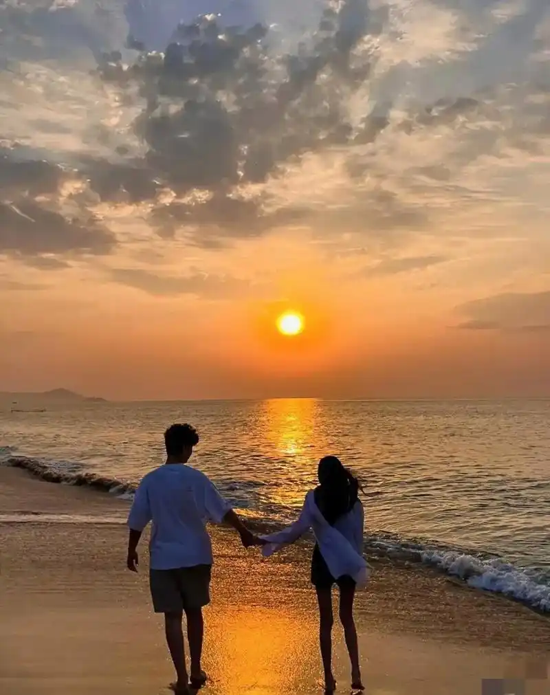 两情侣在海边漫步,边走边笑的聊着天.