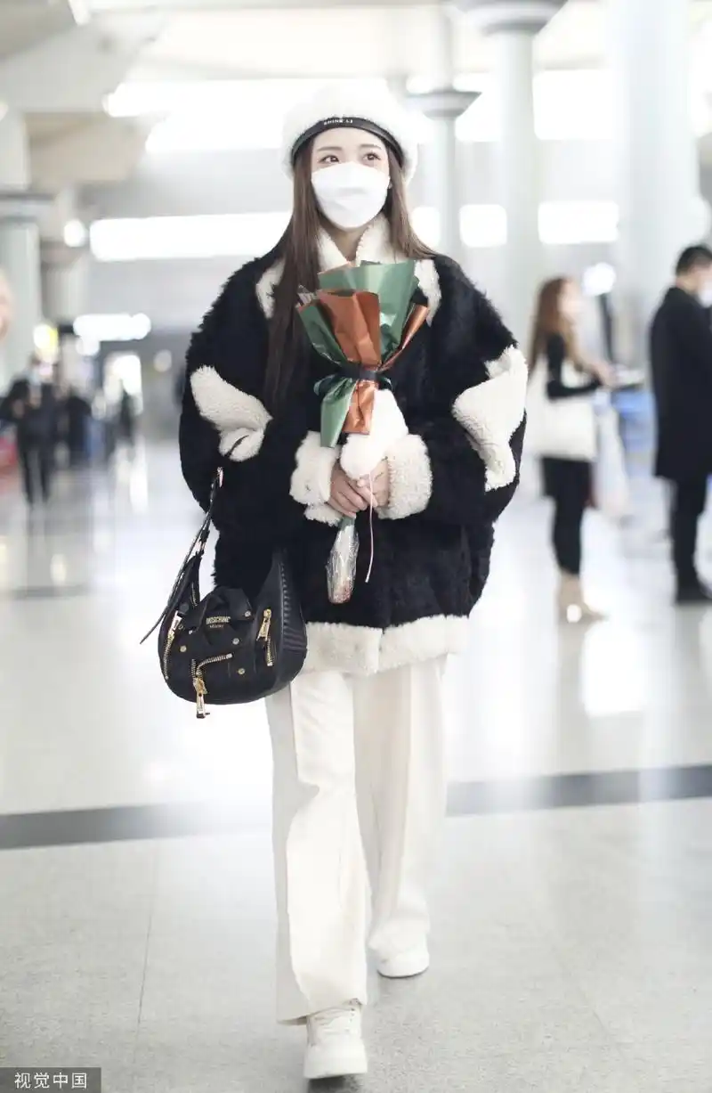 组图:郑乃馨戴白色贝雷帽现身机场 手捧粉丝赠送花束笑眼弯弯