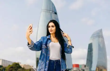 摩天大楼自拍黑发美丽的女孩穿越阿塞拜疆, 使自拍在现代建筑的背景下