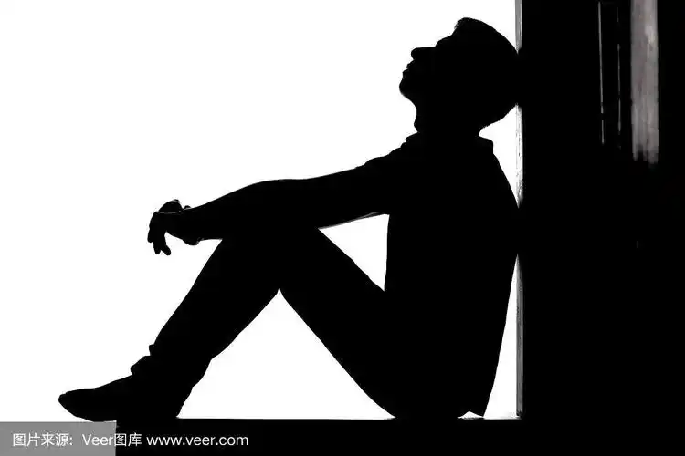 一个年轻沉思的男人坐在地板上,抬头望着希望和绝望,在白色孤立的背景