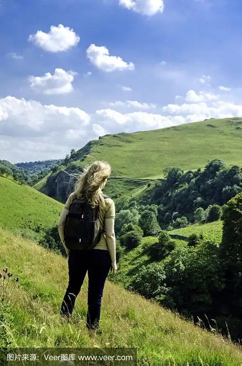 在蓝天下的夏日里,一个女人在英国峰区国家公园里看山