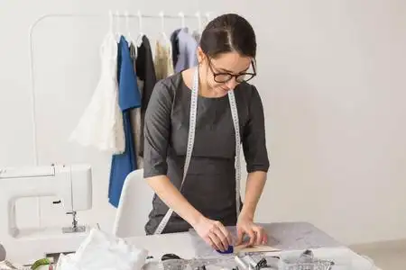 服装师,时装设计师和裁缝概念-漂亮的年轻造型师在工作场所靠近衣架