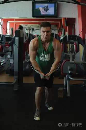 年轻性感的男性健美运动员在健身房训练,使用运动设备和健身设备来改