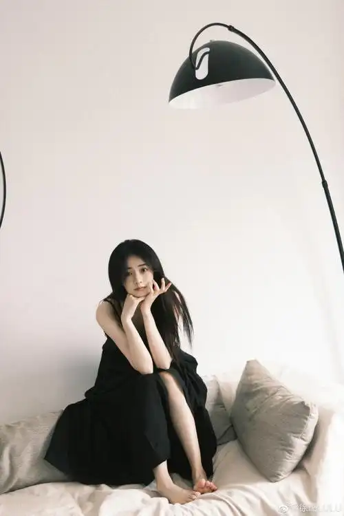 徐璐在个人社交平台晒出一组黑色连衣裙造型随拍,她披散长发在沙发上