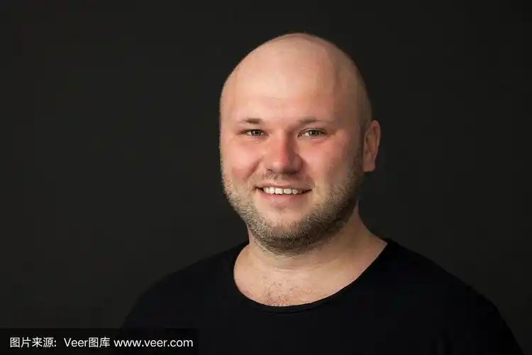 一名35岁剃着光头的大胡子男子的工作室肖像,他穿着黑色t恤,背景是